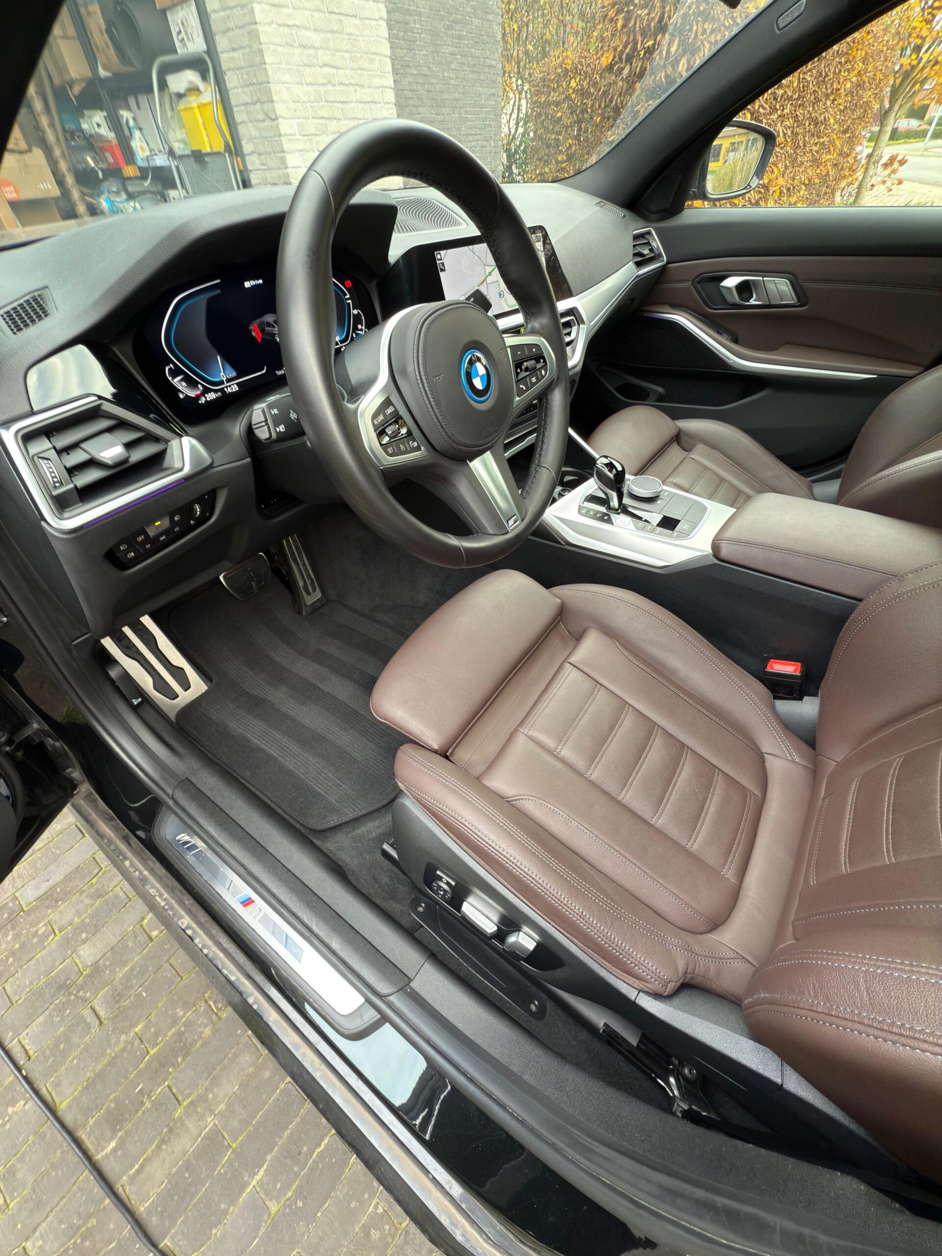 Grondig gereinigd interieur van een BMW met bruine leren zetels en gedetailleerd dashboard na car detailing behandeling.